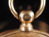 a close up of a gold pocket watch with a black background