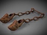 pair of wooden shoes hanging from a chain on a gray surface