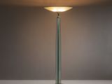 un lampadaire en verre surmonté d'un abat-jour blanc
