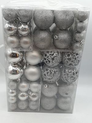 des décorations de Noël argentées, présentées dans une boîte transparente sur fond blanc
