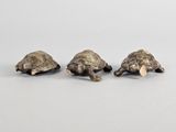 trois figurines de tortues en bronze empilées les unes sur les autres