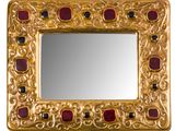 une image représentant un miroir en or orné de pierres rouges et noires