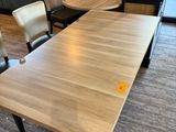 une longue table avec des chaises et un banc dans un coin