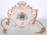 une assiette rose et dorée sur laquelle figure un blason