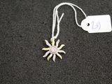 un collier en argent et en or orné d'un pendentif en forme de soleil