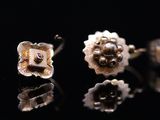 two silver and gold flower earrings on a black surface