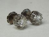 deux paires de boucles d'oreilles en diamant posées sur une surface blanche