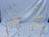 pair of white wrought garden chairs on a white cloth