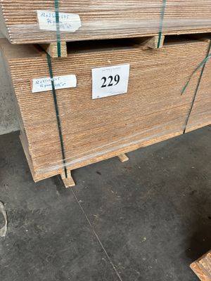 Deux palettes de contreplaqué sont empilées sur des palettes dans un entrepôt.