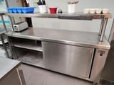 un plan de travail en acier inoxydable dans une cuisine professionnelle, sur lequel sont posés des casseroles et des ustensiles