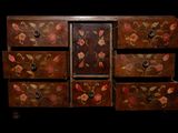 a wooden chest of drawers with flowers painted on it