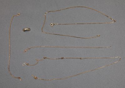 plusieurs types différents de colliers en or posés sur un fond gris
