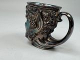 a silver cup with a face on it on a table
