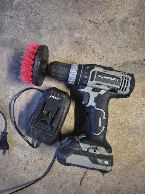 une perceuse filaire et une brosse posées par terre