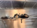 many pots and pans on the shelf in the kitchen