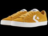 a close up of a pair of yellow sneakers on a black background