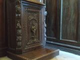 une armoire en bois ornée de sculptures, placée dans un coin de la pièce