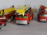 several toy fire trucks are lined up on a white surface