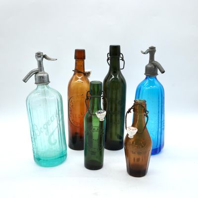 several different colored glass bottles are lined up on a white surface