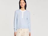 une photo d'une femme portant un pull bleu et un pantalon beige