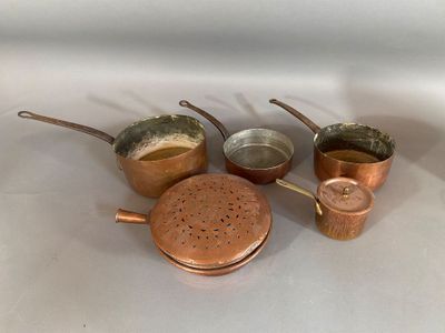 five copper pots and pans sitting on a white surface