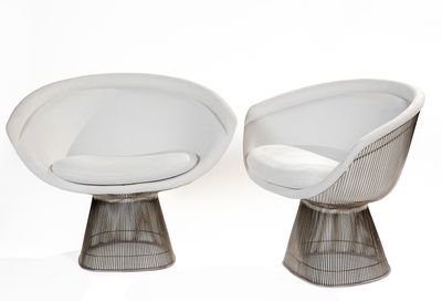 two white chairs with a white cushion and a white cushion