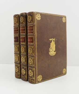 trois livres marron aux tranches dorées, posés sur une surface blanche