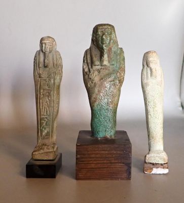 Quatre statues de l'Égypte antique sont exposées sur une table devant un mur blanc