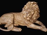 a statue of a lion laying down on a black background