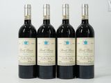 four bottles of wine are lined up on a white surface