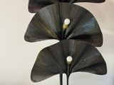 a large metal sculpture of three leaves on a table