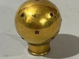 une boule dorée ornée d'étoiles, posée sur un fond blanc