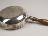 an old silver plate with a wooden handle sitting on a table