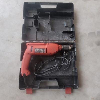 a corded drill in a plastic case on the floor