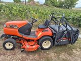 an orange lawn mower parked in a field next to a vineyard
