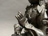 silver statue of a woman sitting on a rock holding a bird