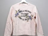 the pink sweatshirt is hanging on a hanger on the wall