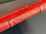 an old red book sitting on top of a table next to a chair