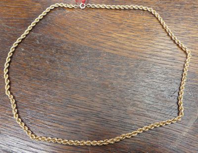 un gros plan d'un collier en or posé sur une table en bois