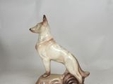 figurine of a german shepherd dog on a rock on a white background
