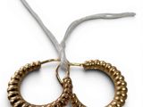 two gold hoop earrings on a white background with a white ribbon