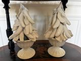 une paire de sapins de Noël en céramique blanche posés sur une table devant une chaise