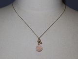 necklace with a pink rose pendant and a gold chain on a mannequin
