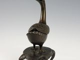 bronze statue of a bird on a stool with a white background