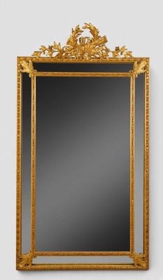 un miroir à cadre doré accroché à un mur blanc sur fond noir