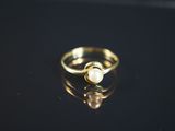 Gros plan sur une bague en or ornée d'une perle