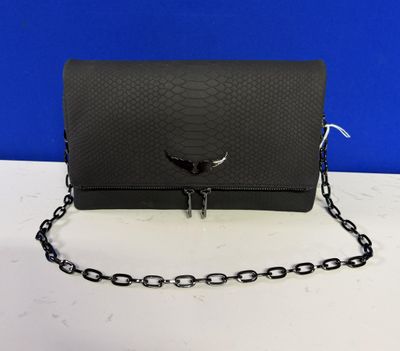 La pochette en peau de serpent noire est entourée d'une chaîne