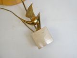 une sculpture en or représentant un oiseau, posée sur une table blanche