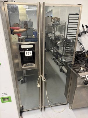 un grand réfrigérateur en acier inoxydable dans une cuisine dotée de nombreux plans de travail