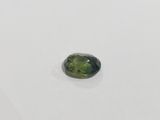 a close up of a green tourmaline stone on a white surface